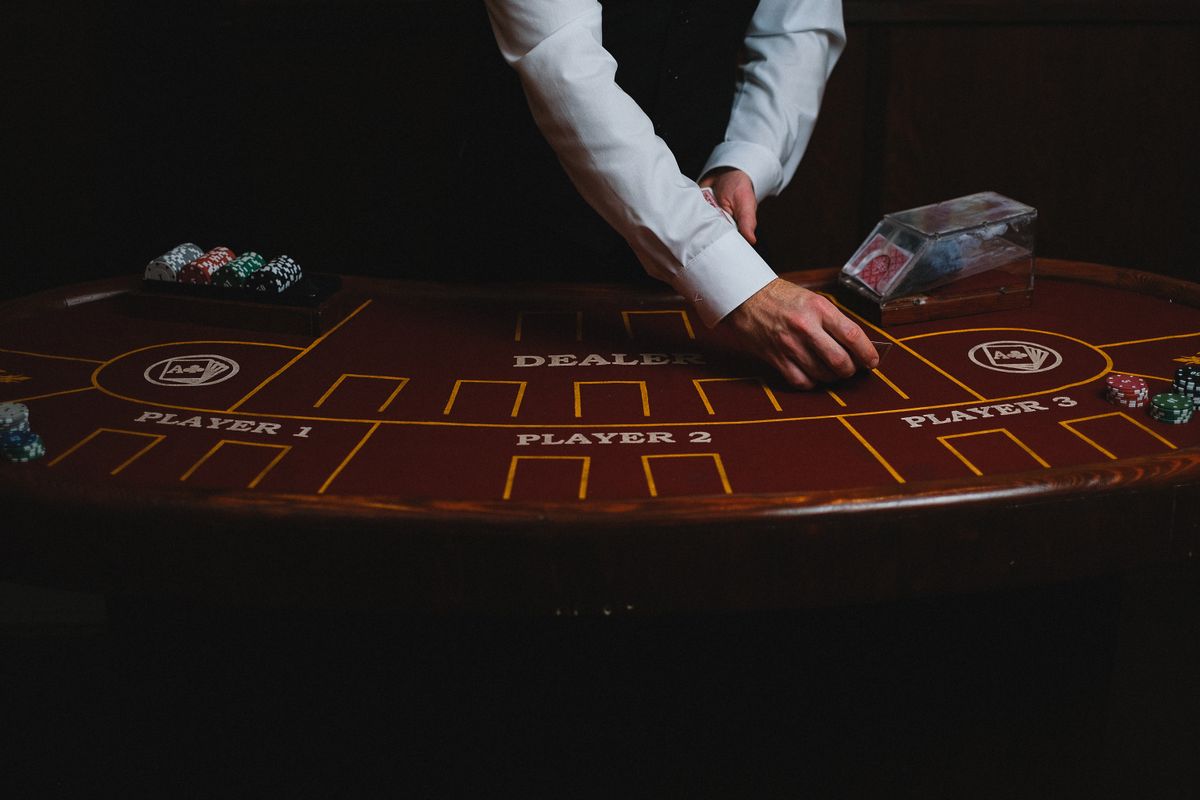 Dealer wanita di meja live casino dengan kartu remi dan roda roulette