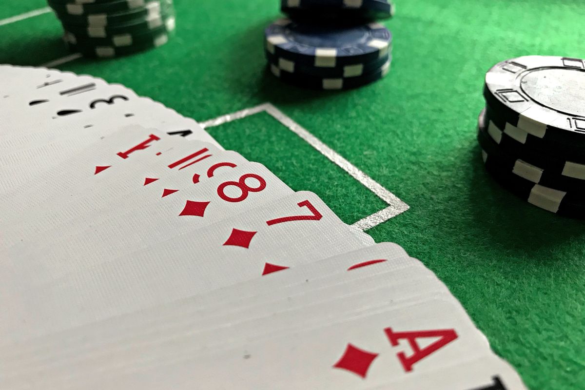 Tumpukan chip poker warna-warni di atas meja hijau